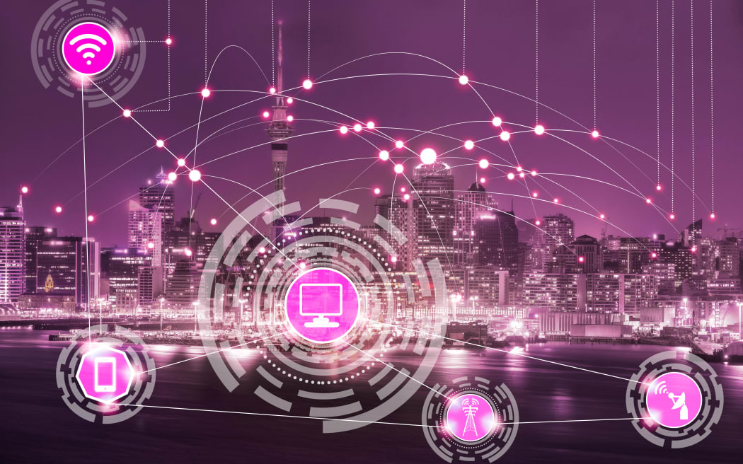 Smart city wireless communication network with graphic showing concept of internet of things ( IOT ) and information communication technology ( ICT ) against modern city buildings in the background.