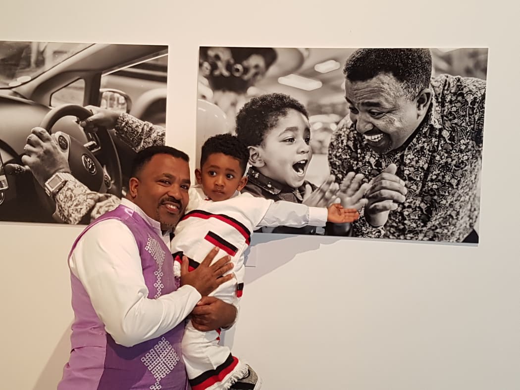 Niguisse Fenja with his photos and son Emmanual.