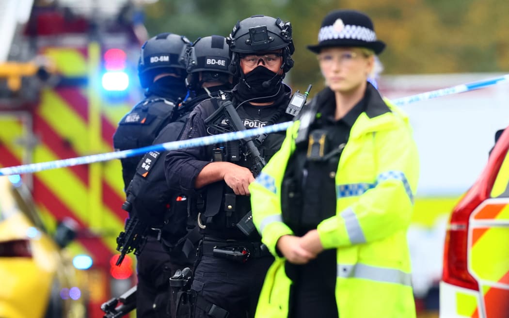 Armed police officers stand with their weapons inside a Police cordon near Heaton Park Hebrew Congregation synagogue in Crumpsall, north Manchester, on October 2, 2025, following an incident at the synagogue. Four people were injured and a suspected perpetrator shot by police Thursday after and a car was driven towards people outside a synagogue in Manchester, northern England, and one person was stabbed, officials said. Greater Manchester Police declared a "major incident" shortly after 9:30am (0830 GMT) after officers were called to the Heaton Park Hebrew Congregation Synagogue in the Crumpsall neighbourhood of the city. (Photo by Paul Currie / AFP)