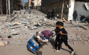 Young boys push a loaded trolley in Rafah in the southern Gaza Strip on December 10, 2023, as battles between Israel and the Palestinian Hamas movement. Israeli forces pushed into southern Gaza on December 10, where hundreds of thousands of civilians have fled in search of shelter from bombardments and intense fighting with Hamas militants. (Photo by MOHAMMED ABED / AFP)