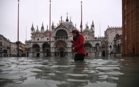 A woman crosses the flooded St. Mark's square by St. Mark's Basilica after an exceptional overnight "Alta Acqua" high tide water level, early on 13 November, 2019 in Venice.