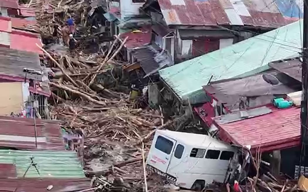 Vehicles are seen amongst the debris swept away by flash flood at the height of Typhoon Kalmaegi, along a street of a village in La Carlota city, Negros Oriental province, central Philippines
