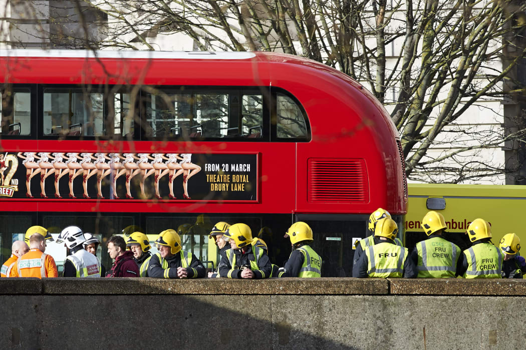 Ambulance and fire service workers beside a stationary London bus on Westminster Bridge.