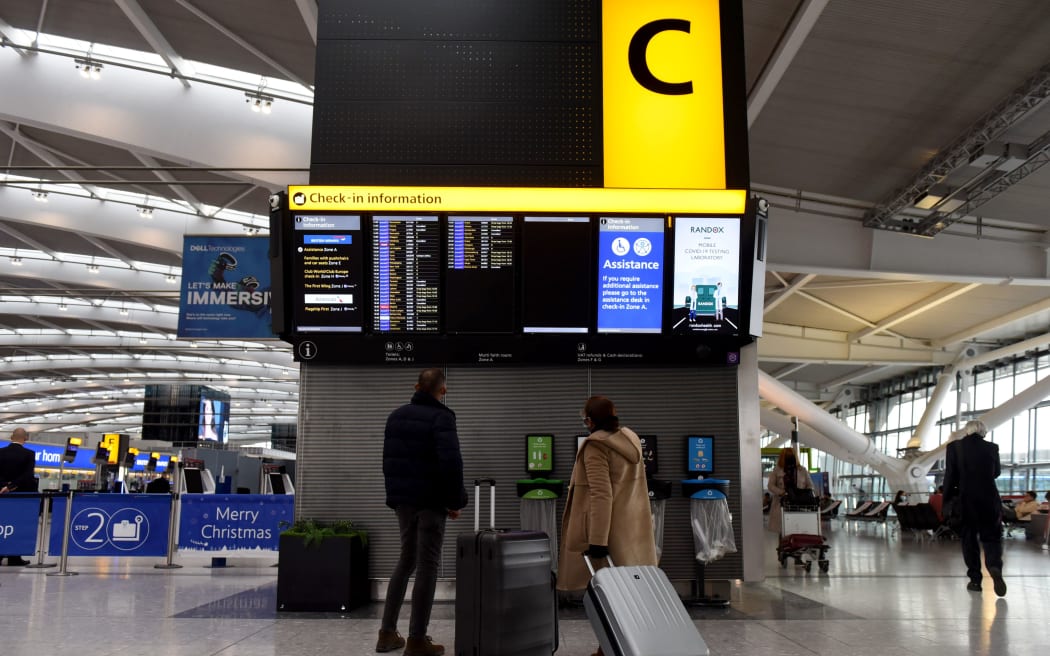 LONDON, ENGLAND - DECEMBER 21: Travellers look at the departures board at an almost deserted departures hall at Terminal 5 of Heathrow Airport in west London on December 21, 2020, as a string of countries around the world banned travellers arriving from the UK