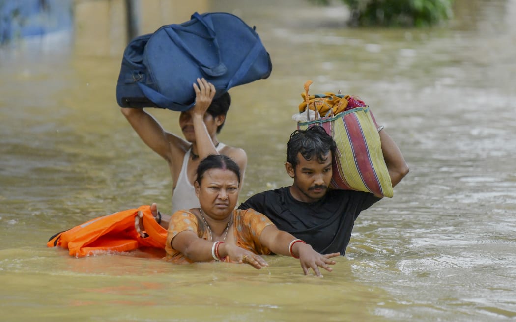 Flood-affected villagers wade through water to reach safer areas following heavy rainfall at Badkhal village, on the outskirts of Agartala, India, on June 1, 2025. (Photo by Abhisek Saha / Middle East Images / Middle East Images via AFP)