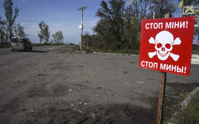This photograph taken in Izyum, eastern Ukraine on September 29, 2022, shows a landmine warning sign next to a road, amid the Russian invasion of Ukraine. (Photo by Juan BARRETO / AFP)