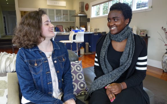 2 students sit on a couch at home