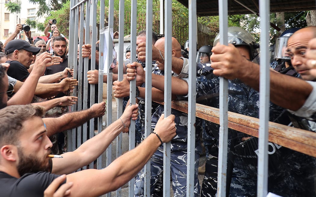 Protesters try to pull out a gate to the Justice Palace in Beirut, demanding the release of two people involved in a bank heist the prior week. Amid Lebanon's painful currency crisis, depositors have been locked out of their foreign currency savings by banking controls that have gradually tightened since 2019. Banks have in the past been targeted in street protests, often leaving their windows and ATMs smashed. Now, many frustrated depositors, unable to transfer or withdraw their dollar deposits, have resorted to desperate bank heists to free their money. 19 September 2022.
