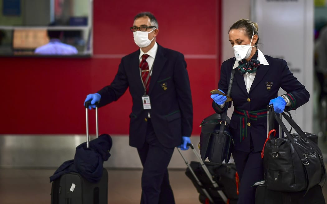 Crew members wearing face masks as a preventive measure against the spread of the Covid-19 coronavirus arrive at Ezeiza International Airport in Buenos Aires, on March 12, 2020.
