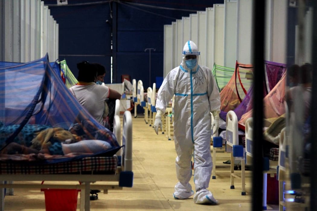 A doctor walks past Covid-19 patients at a makeshift facility created inside a sports complex, amidst the spread of coronavirus cases, in New Delhi, India on May 13, 2021.