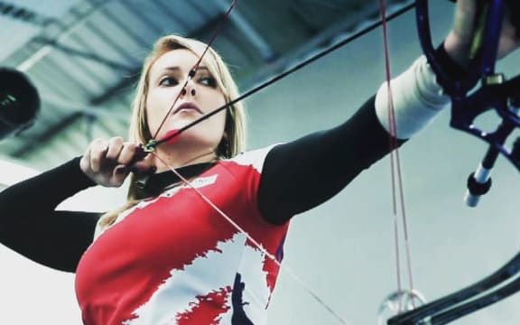 Danielle Brown stands in position with her archery bow.