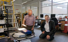 The wireless power concept from a roadway to a vehicle (lighting a light) with John Boys (left) and Grant Covic (right)