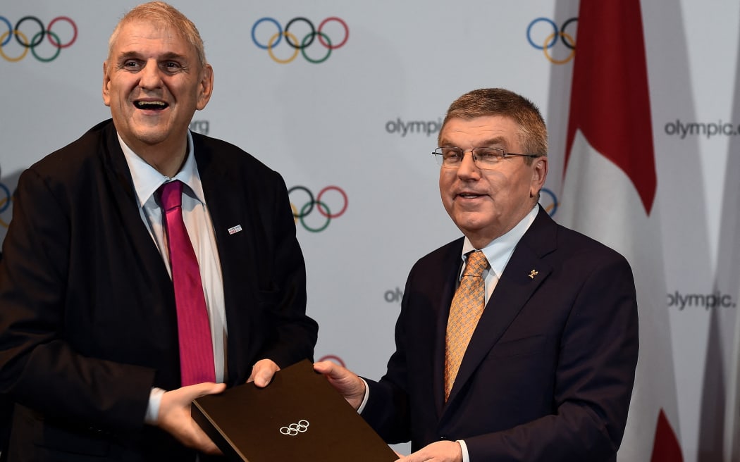 International Olympic Committee (IOC) President Thomas Bach (R) hands a document to Lausanne mayor Daniel Brelaz (L) after the Host cities contract signing following Lausanne winning the 2020 Youth Winter Olympic city, during the 128th International Olympic Committee (IOC) session in Kuala Lumpur on July 31, 2015.    AFP PHOTO / MANAN VATSYAYANA (Photo by MANAN VATSYAYANA / AFP)