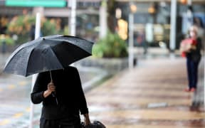 Woman walks in the rain with an umbrella.