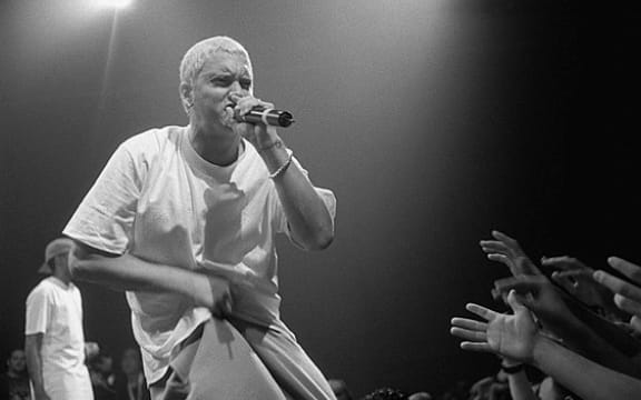 A black and white picture of Eminem singing in front of a crowed