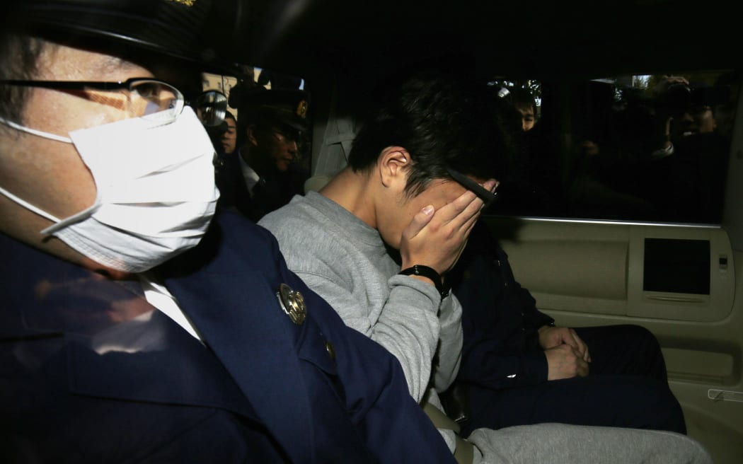 Suspect Takahiro Shiraishi (C) covers his face with his hands as he is transported to the prosecutor's office from a police station in Tokyo on November 1, 2017.