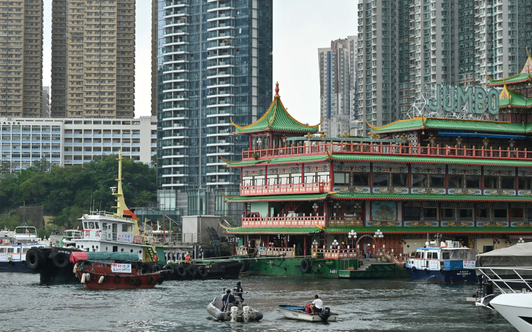 A tug (L) pulls Hong Kong's Jumbo Floating Restaurant, an iconic but aging tourist attraction designed like a Chinese imperial palace, as its towed out of Aberdeen Harbour on June 14, 2022, after years of revitalisation efforts went nowhere. (Photo by Peter PARKS / AFP)