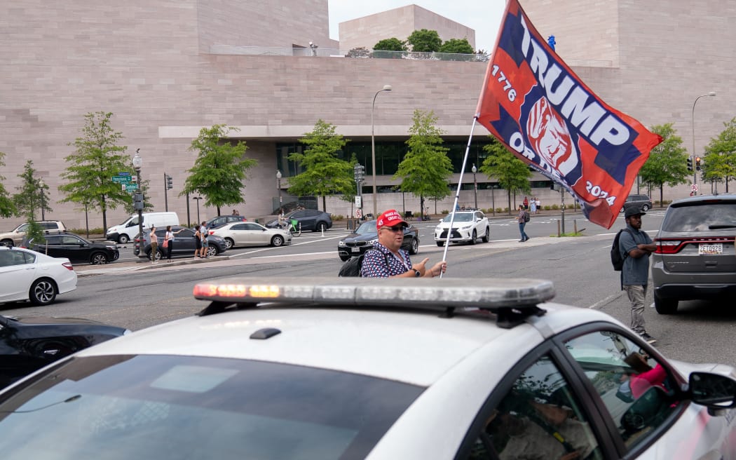 A supporter of former US President Donald Trump flies a flag outside the E. Barrett Prettyman US Courthouse in Washington, DC, on August 3, 2023, ahead of Trump's arraignment.