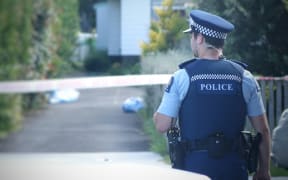 A police officer near the Te Atatu house where Cun Xiu Tian, 69, was found dead.