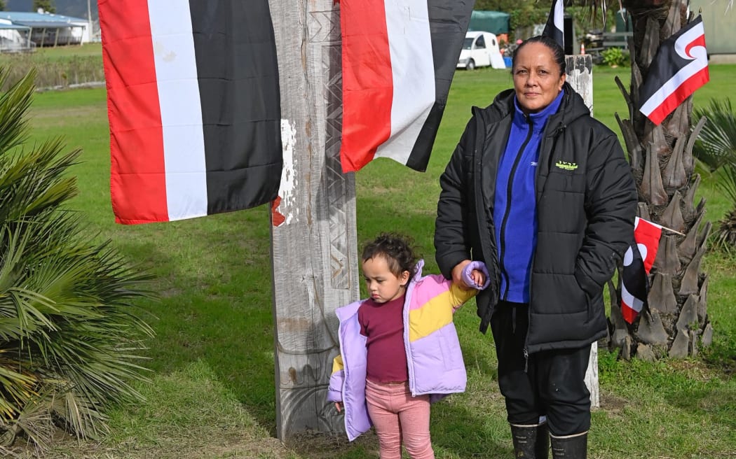 Tina Olsen-Ratana pictured with her moko Akakaingaro in front of Hamoterangi/Ruataupare, presented in pou form. The pou represents inclusiveness of all whānau affected by the loss of whenua.