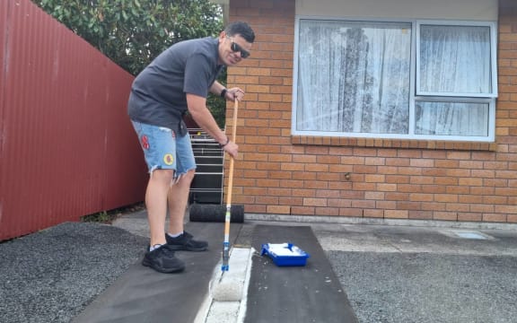 NPDC chief executive Gareth Green repainting parking marking at the council-owned List St pensioner flats.