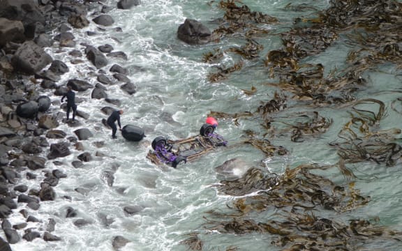 Police attach black floats to the car wreck in preparation for its removal from the bay.