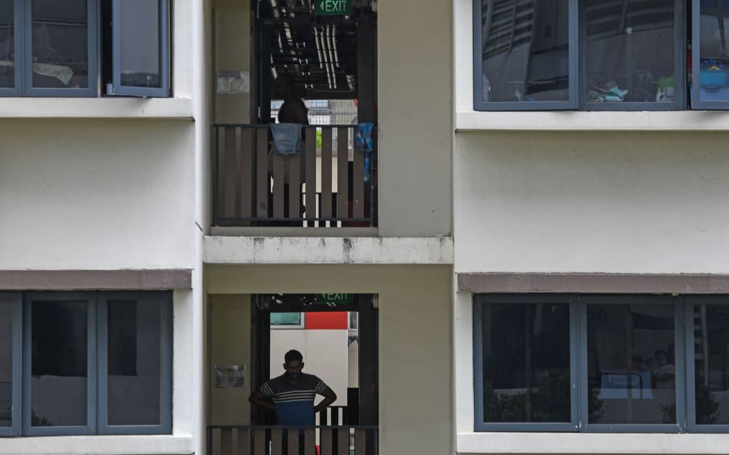 A migrant worker stands along the corridor at a foreign workers' domitory, currently under isolation as a preventive measure against the spread of the COVID-19 novel coronavirus, in Singapore on April 27, 2020. -