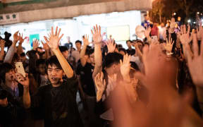 Pro-democracy supporters celebrate after pro-Beijing candidate Junius Ho lost a seat in the district council elections in Tuen Mun district of Hong Kong, early on November 25, 2019.