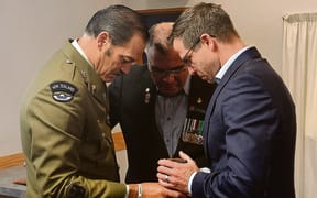 Willie Apiata presents his Victoria Cross medal to MP Chris Penk.