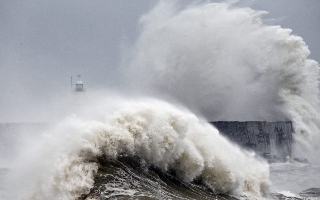 Waves crash over Newhaven Lighthouse and the harbour wall in Newhaven, southern England on 2 November 2023, as strong winds and heavy rain from Storm Ciaran hit Britain. High winds and heavy rain brought by storm Ciaran caused major disruption in southern England on November 2, 2023, with shipping from the port of Dover suspended for several hours and hundreds of schools closed. Winds of up to 100/110 km/h were expected in the morning, and up to 100 km/h in the afternoon, according to the weather forecast on the British government website. (Photo by GLYN KIRK / AFP)