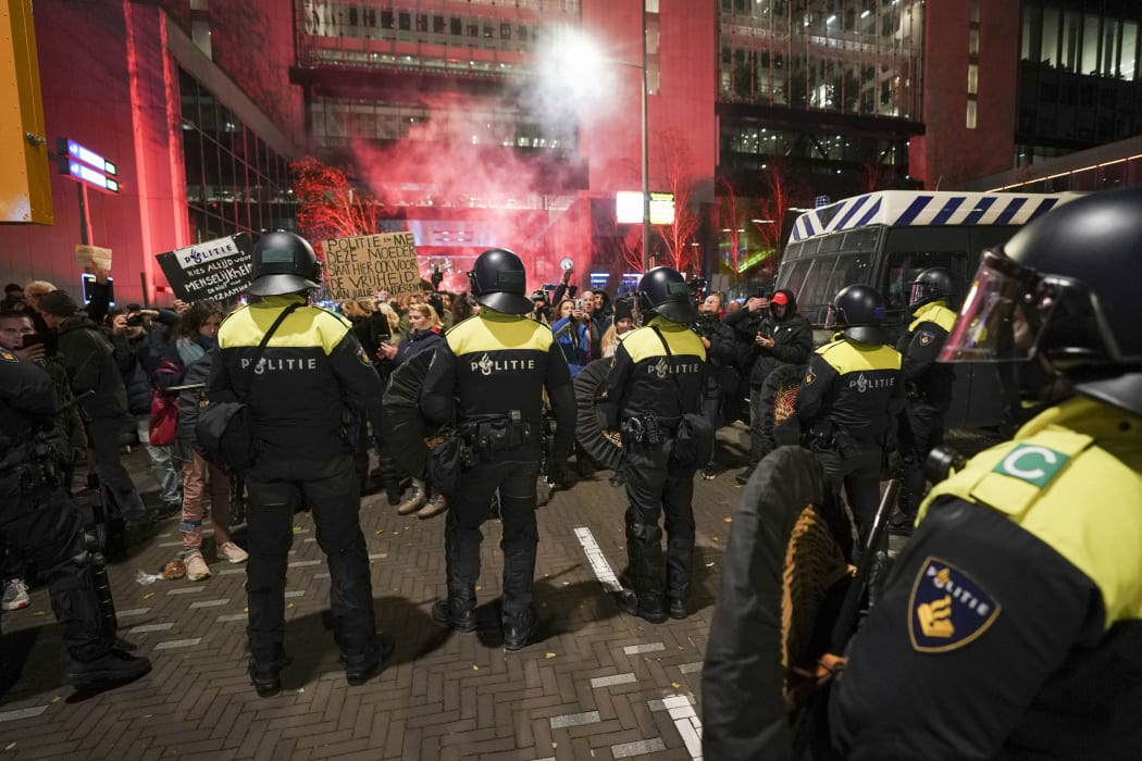 Riot police officers face protesters as they gather in the Hague,during a press conference of Dutch Prime Minister held to announce new Covid-19 restrictions.
