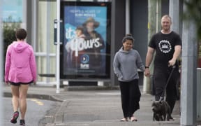 Pedestrians practise social distancing in response to the COVID-19 coronavirus outbreak along a street of Lower Hutt, near Wellington, on April 20, 2020.