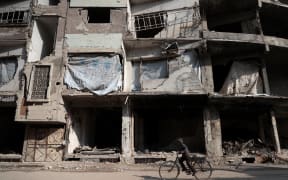 A Syrian boy cycles past damaged buildings in the rebel-held town of Douma, on 30 December 2016, on the first day of a nationwide truce.