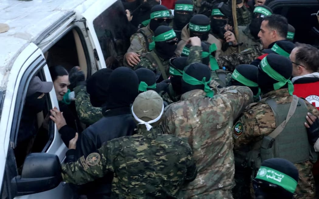 Hamas militants gather around a vehicle as they prepare to release the Israeli hostages at the weekend.