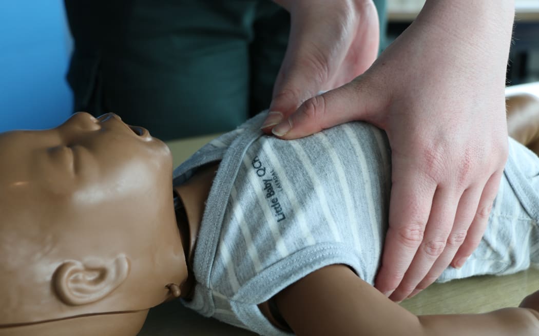 St John’s Three Steps for Life delivery lead Mia Noyes performing chest compression using her thumbs for CPR on an infant manikin.