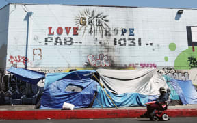 LOS ANGELES, CALIFORNIA - JUNE 28: A person passes an encampment of unhoused people in the Skid Row community on June 28, 2024 in Los Angeles, California. The U.S. Supreme Court ruled today that cities can ban people, including those who are homeless, from camping and sleeping outdoors in public places, overturning lower court rulings. Skid Row is home to thousands of people who are either experiencing homelessness on the streets or living in shelters.   Mario Tama/Getty Images/AFP (Photo by MARIO TAMA / GETTY IMAGES NORTH AMERICA / Getty Images via AFP)