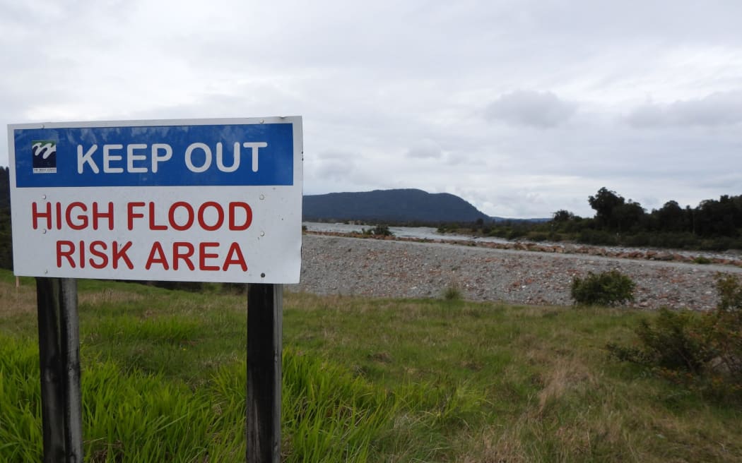 A West Coast Regional Council warning sign on the south bank of the Waiho River, just west of the main road bridge. Motels formerly close to the sign were bought and removed by the council in 2014 due to the hazard posed by the river and risk of stopbank failure.