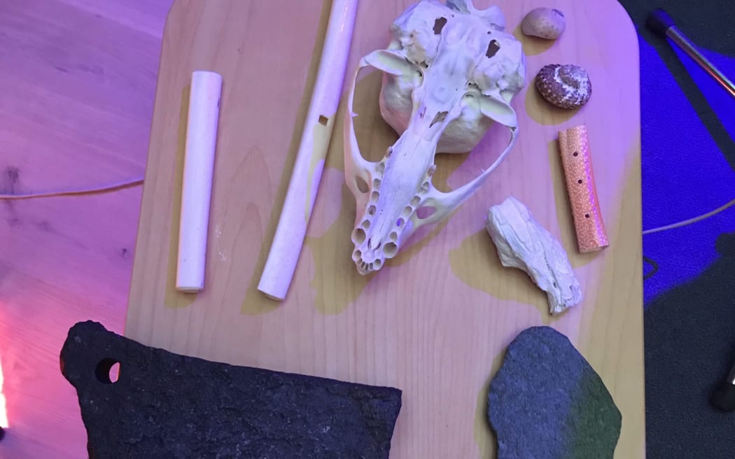 A skull, two shells, and a variety of flutes sitting on a low table.