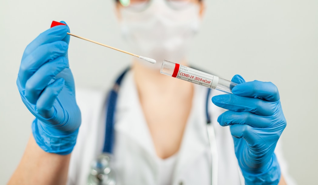 Test for coronavirus Covid-19. Female doctor or nurse doing lab analysis of a nasal swab in a hospital laboratory. Medical technologist holding a COVID-19 smear kit, wearing protective gloves from