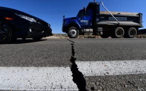 Vehicles drive over a crack on Highway 178 south of Trona, after a 6.4-magnitude earthquake hit in Ridgecrest, California.