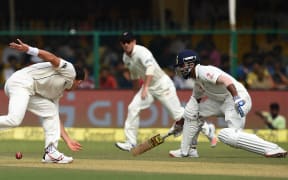 India's Lokesh Rahul, right, watches as New Zealand's Trent Boult, left, makes an unsuccessful attempt to stop a shot by Murali Vijay during the first day of the first Test match at Green Park Stadium in Kanpur on 22 September 2016.