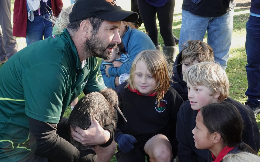 Northland Regional Council kiwi handler Rolf Fuchs shows children from Opua School a kiwi.