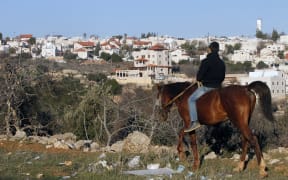 A Palestinian boy riding his horse past the Israeli settlement of Givat Harsina.