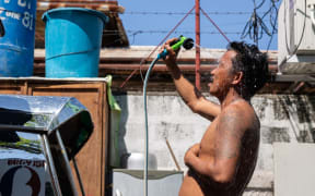 A man showers with a hose during hot weather in Manila on April 28, 2024. The Philippines will suspend in-person classes in all public schools for two days due to extreme heat and a nationwide strike by jeepney drivers, the education department said on April 28. (Photo by Earvin Perias / AFP)