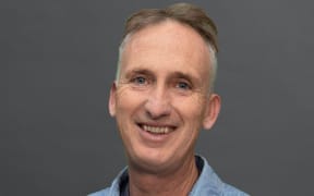 Mark Amery smiles wearing a pounamu pedant