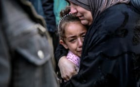 A Palestinian woman holds a child as they mourn their relatives killed in Israeli bombardment in front of the morgue of the Al-Shifa hospital in Gaza City on March 15, 2024, amid the ongoing conflict between Israel and the Palestinian Hamas movement.