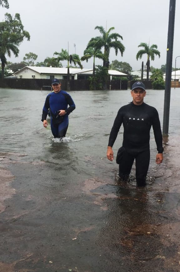 A handout picture provided by Queensland Police Service, taken on February 2, 2019 and release on February 3 shows two police officers wading in flood waters in Townsville. -