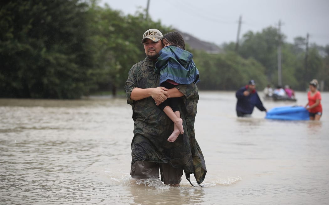 People walk down a flooded street as they evacuate their homes after the area was inundated with flooding from Hurricane Harvey.