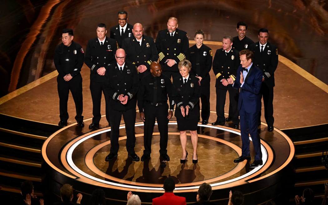 (From L) Los Angeles Fire Department (LAFD) Captain Erik Scott, LAFD helicopter pilot Jonith Johnson Jr. and Pasadena Fire Captain Jodi Slicker speak onstage next to US comedian and host Conan O'Brien during the 97th Annual Academy Awards at the Dolby Theatre in Hollywood, California on March 2, 2025. (Photo by Patrick T. Fallon / AFP)