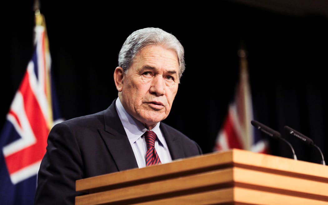 Winston Peters standing in the Beehive Theatre, making an announcement.